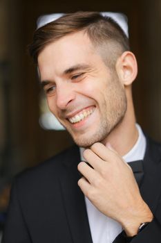 Portrait of young smiling man wearing black suit with bow tie and white shirt. Concept of male model.