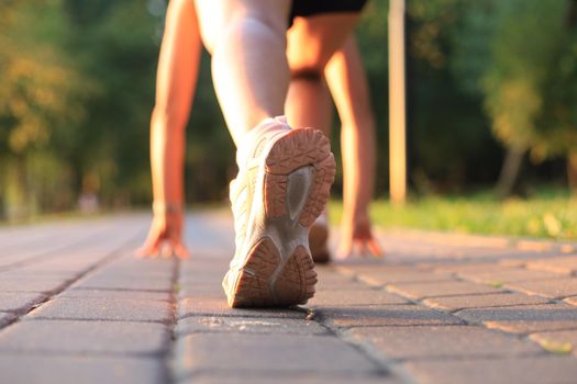 Runner feet running on road closeup on shoe, outdoor at sunset or sunrise