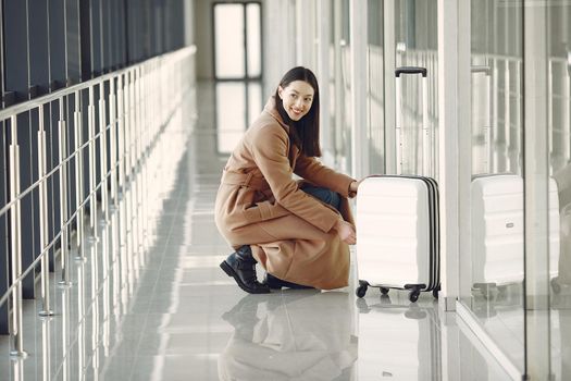 Woman at the airport. Girl with suitcase. Lady in a brown coat.