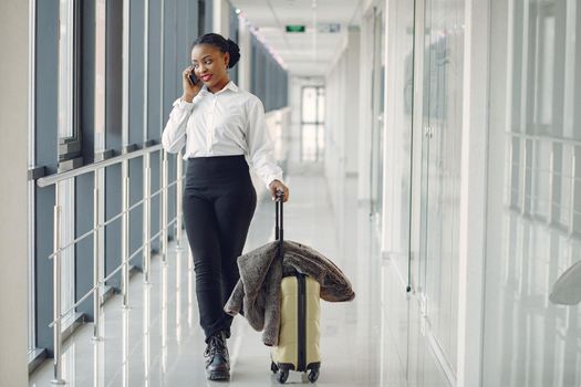 Black woman at the airport. Girl with suitcase. Lady in a white shirt.