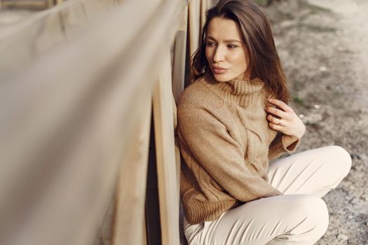 Woman in a brown sweater. Girl in a spring city. Lady by the building.