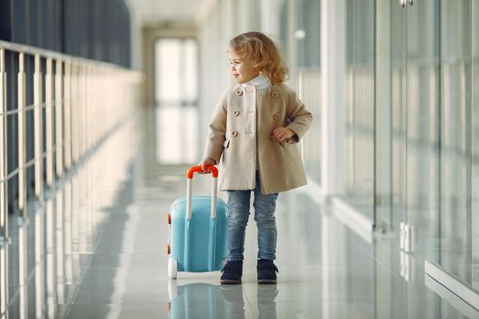 Child at the airport. Little girl with a suitcase. Girl in brown coat.