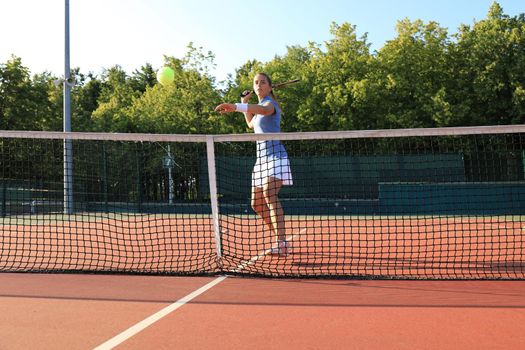 Pretty sportswoman with racquet at the tennis court. Healthy lifestyle