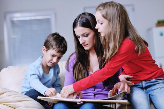 young mother read book to their kids at modern new home living room indoor