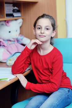 happy young school girl doing homework at home