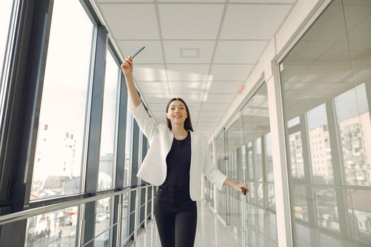 Woman at the airport. Girl with suitcase. Lady in a white jacket. Woman holds passport in her hands.