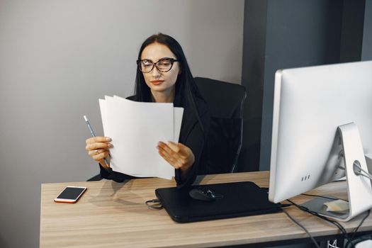 Lady with glasses. Manager is sitting at the computer. Businesswoman works in her office.