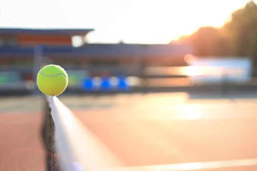 Bright greenish yellow tennis ball hitting the net