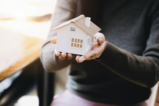 Female hand holding a house model, insurance concept and home loan