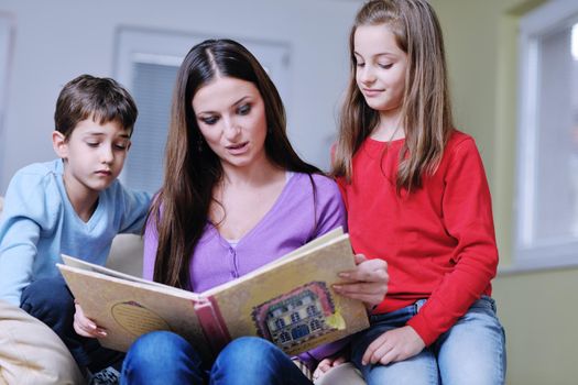 young mother read book to their kids at modern new home living room indoor