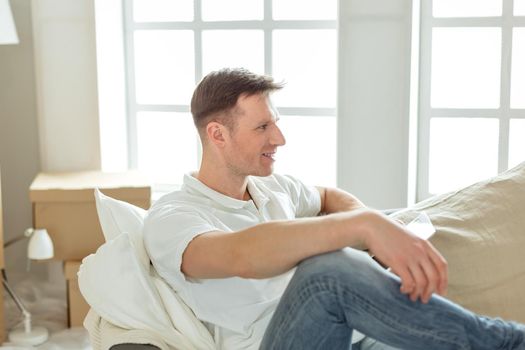 close up. happy man sitting on the couch in his new apartment
