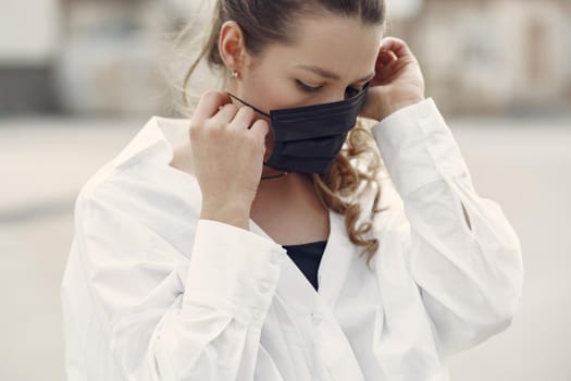 Woman in the city. Person in a mask. Coronavirus theme. Woman in a white shirt.