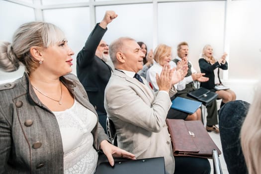 side view. smiling business seminar listeners applauding together. business and education