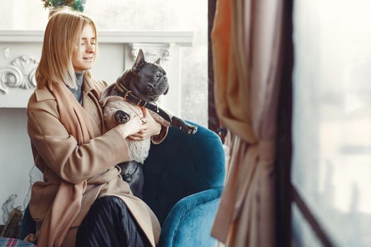 Woman with dog. Lady in a brown coat. Girl play with bulldog. Woman in a cafe.