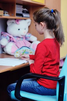 happy young school girl doing homework at home