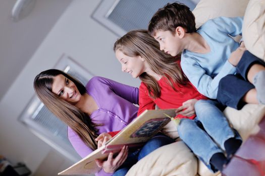 young mother read book to their kids at modern new home living room indoor