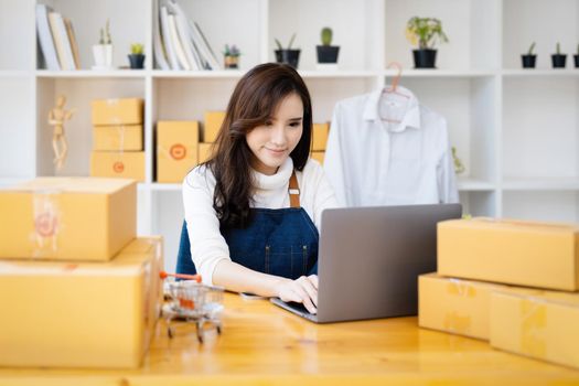 Work from home. happy women selling products online Start a small business owner by using laptop computer to calculate prices and prepare for postage