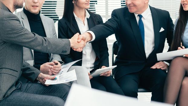 boss shaking hands with an employee during a work meeting. the concept of teamwork