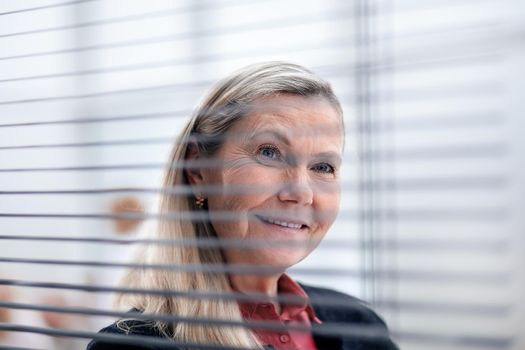 close up. senior business woman looking through office blinds