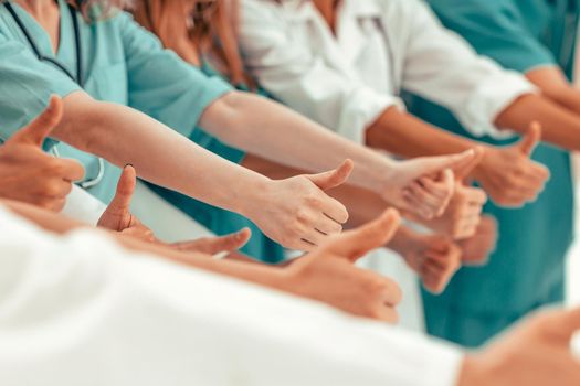 close up. group of doctors showing thumbs up. success concept