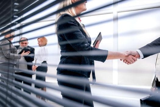through-blinds. confident businesswoman shaking hands with her business partner. the concept of cooperation