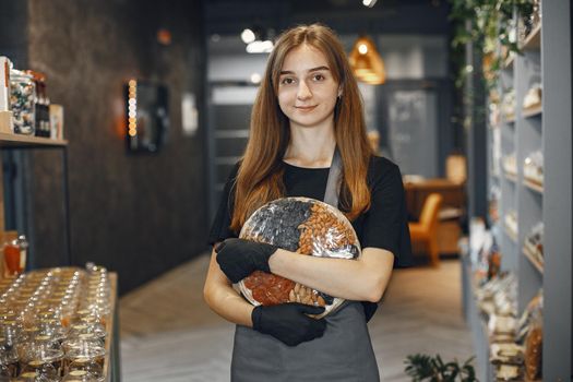 Brunette looks at the camera and smiles. Woman in apron. Lady in the store.