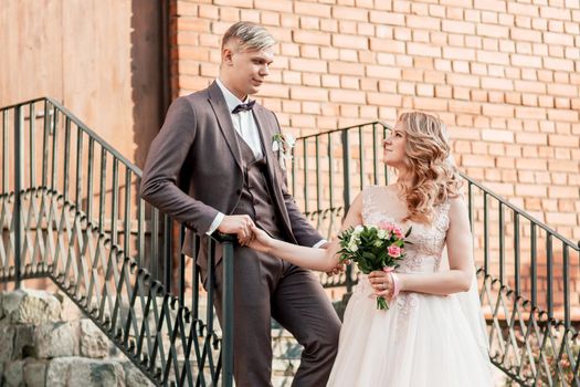 bride and groom standing on the porch of a brick house. holidays and events