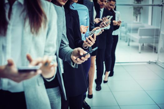 close up. a group of young business people looking at their smartphone screens