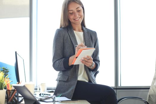 Concentrated young woman writing something down while working in the office