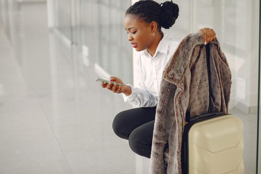 Black woman at the airport. Girl with suitcase. Lady in a white shirt.