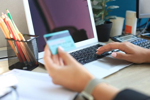 Woman holding credit card on laptop for online shopping concept