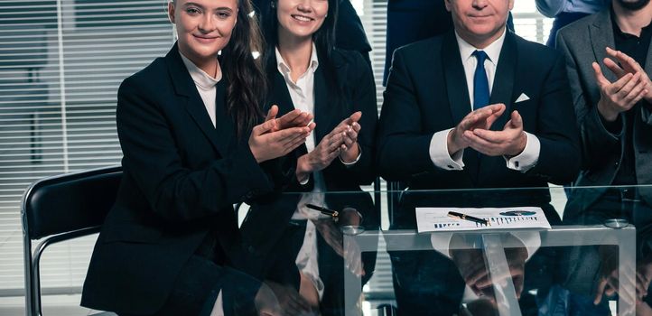 boss and the happy business team applauding their success near the desktop.