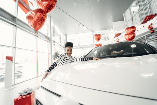 Went shopping today. Shot of an attractive African woman hugs a new car.