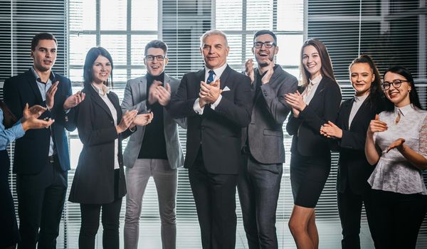 group of happy corporate employees applauding their success