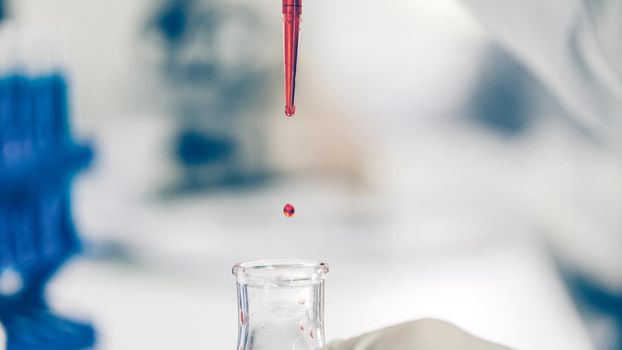 close up. background image of a drop of red liquid in a laboratory pipette. photo with a copy-space.