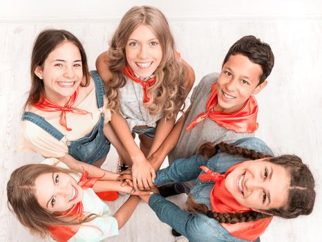 smiling cute children keeping hands together and looking up at the camera