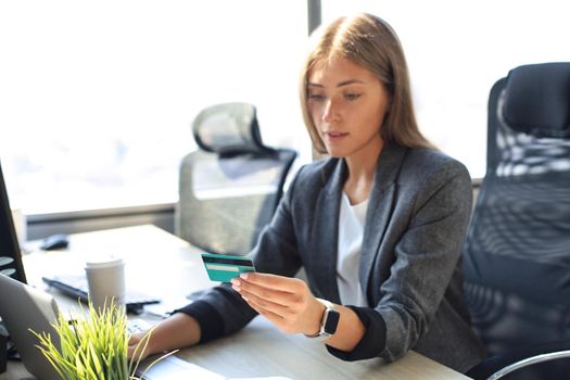 Woman holding credit card on laptop for online shopping concept