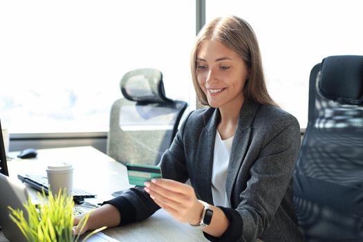 Woman holding credit card on laptop for online shopping concept