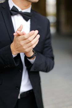 Close up man clapping and wearing black suit with bow tie. Concept of business trip and executive person on conference.