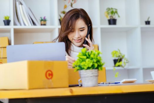 Work from home. happy women selling products online Start a small business owner by using smartphone and laptop computer to calculate prices and prepare for postage