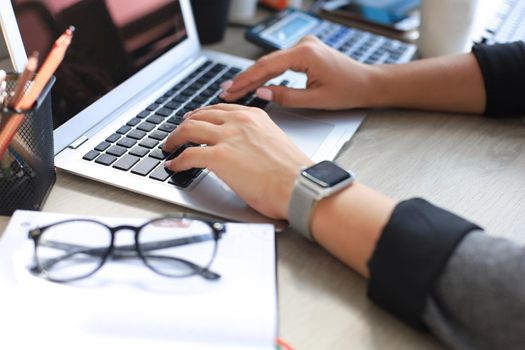 Woman hands pressing keys on a laptop keyboard in office