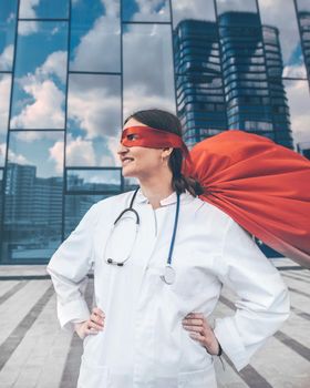 female doctor in a superhero raincoat looks at a city street . photo with a copy-space.