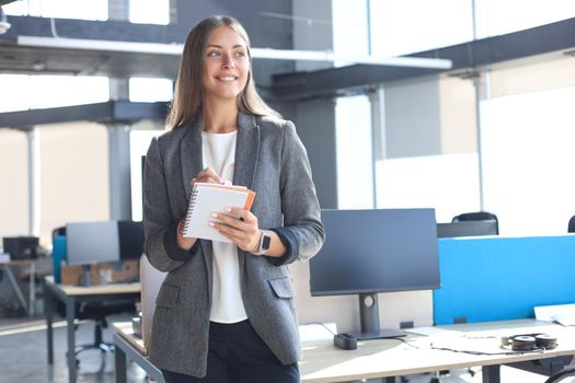 Concentrated young woman writing something down while working in the office