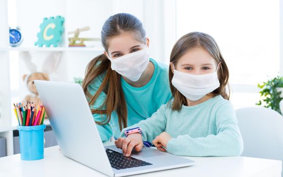 Girls studying at home using laptop during coronavirus pandemic