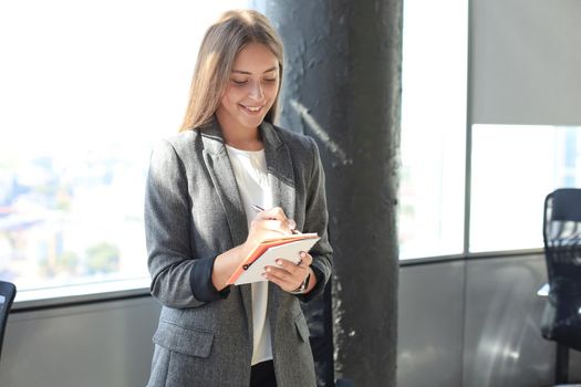 Concentrated young woman writing something down while working in the office