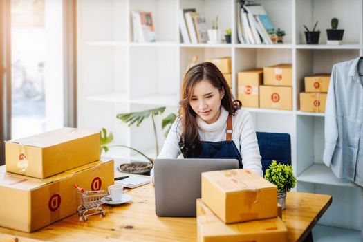 Work from home. happy women selling products online Start a small business owner by using laptop computer to calculate prices and prepare for postage