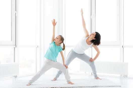 Lovely little girl and pretty woman doing workout at home