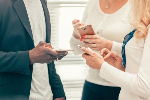 close up. young business people reading messages on their smartphones