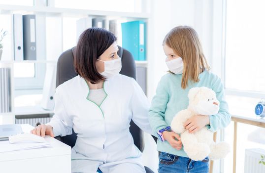 Little girl with teddy bear visiting doctor in clinic