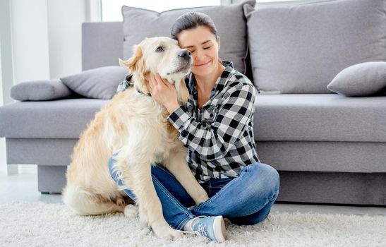 Beautiful woman cuddling lovely dog in light room